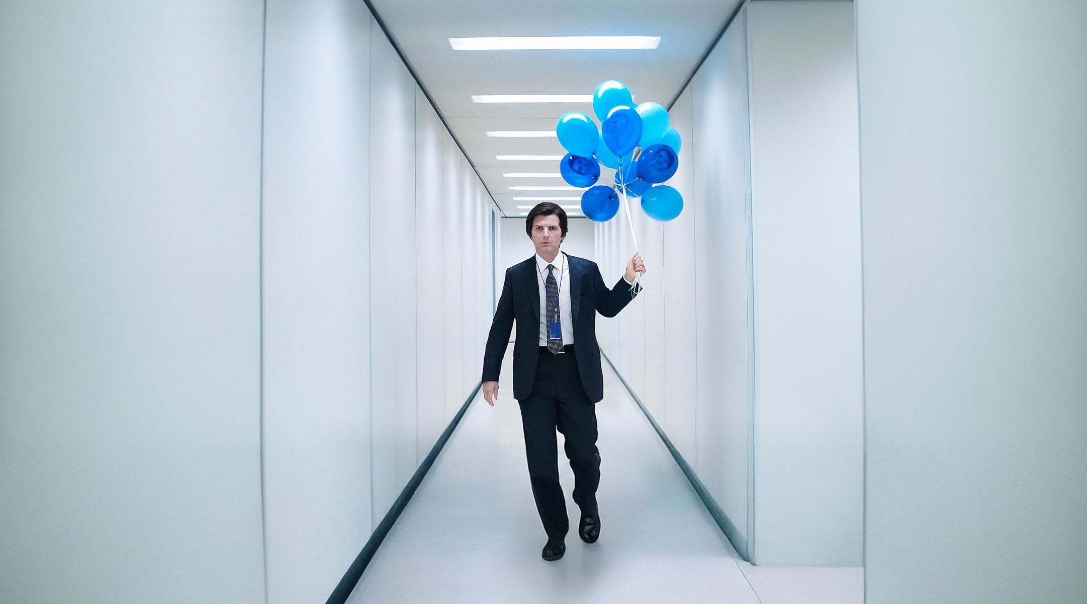 Severance — Mark in a fluorescent corridor with blue balloons